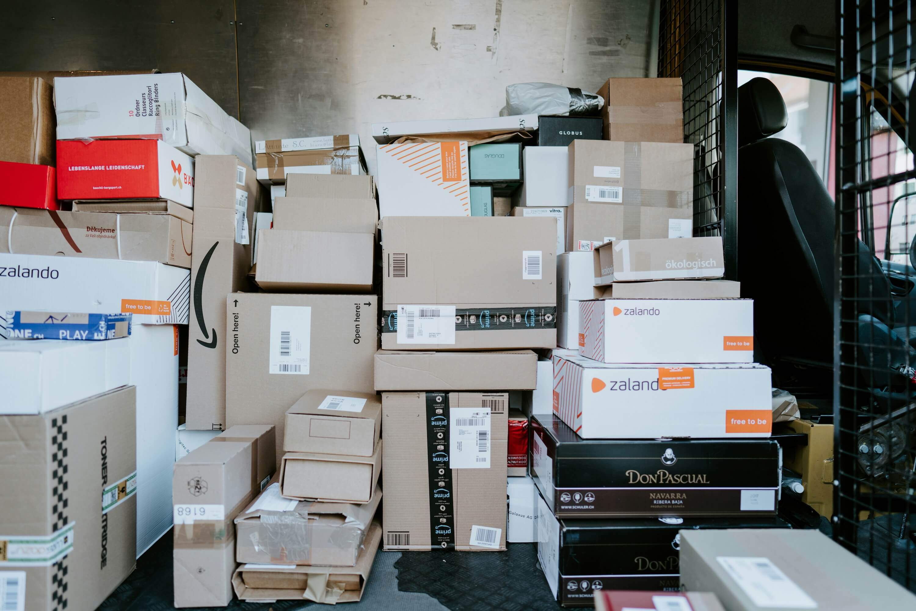  A delivery van filled with stacked cardboard boxes from various brands.